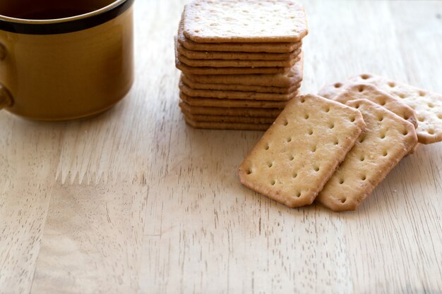 Biscotti del cracker del latte serviti con caffè caldo sullo scrittorio di legno, rottura di tempo