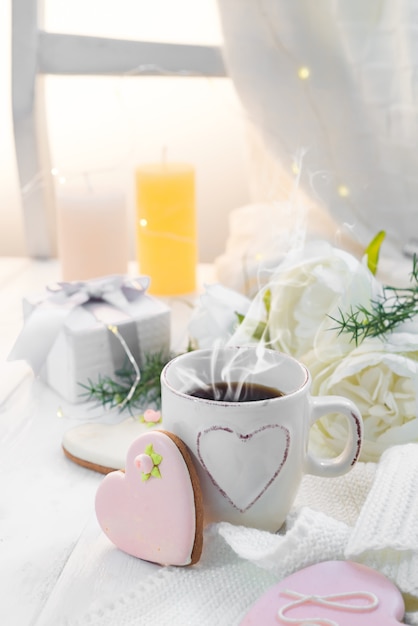 Biscotti del cuore con la tazza di caffè su fondo di legno con il plaid, spazio della copia