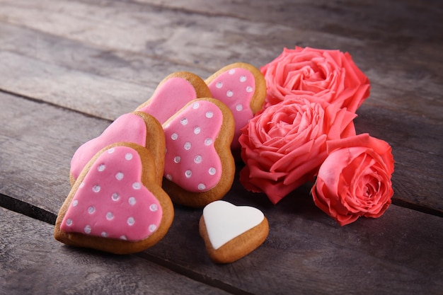 Biscotti del cuore di San Valentino con le rose su fondo di legno