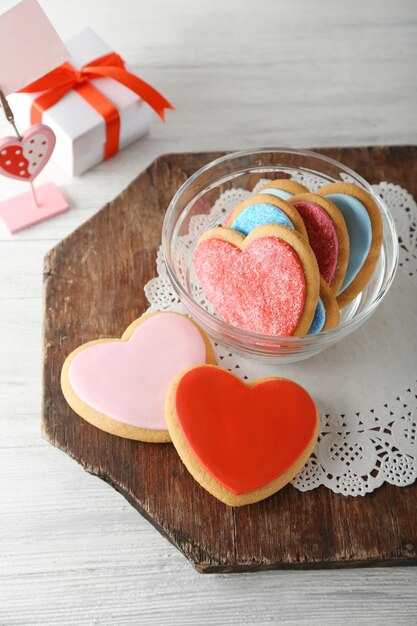 Biscotti del cuore di San Valentino in ciotola di vetro con scatola presente su fondo di legno