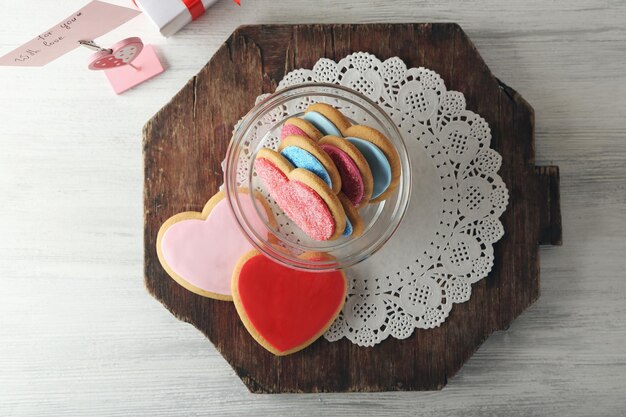 Biscotti del cuore di San Valentino in una ciotola di vetro con la scatola presente sul tavolo in legno vista dall'alto