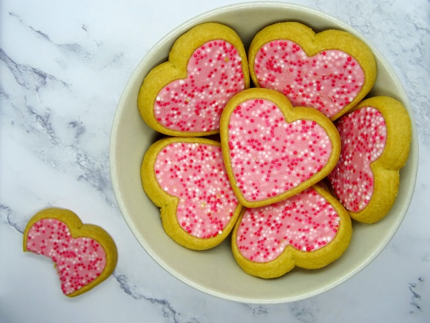 Biscotti del cuore in un piatto e un biscotto morso