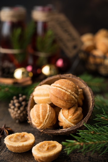 Biscotti del dessert di natale matti con latte condensato bollito su una parete scura con le ghirlande e le decorazioni di natale