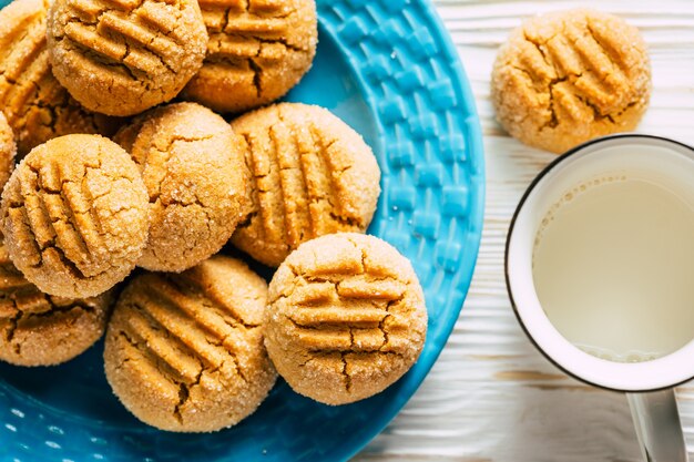 Biscotti di arachidi in piatto blu su fondo di legno bianco