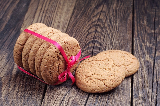 Biscotti di avena dolci legati con nastro rosso su tavola di legno