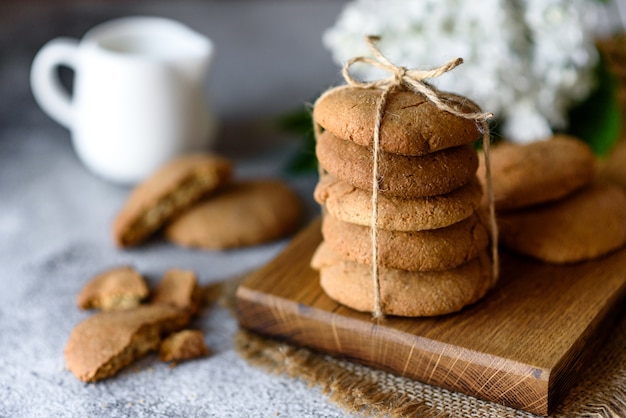 Biscotti di farina d'avena casalinghi su un tagliere di legno sul vecchio fondo della tavola. Concetto di snack cibo sano