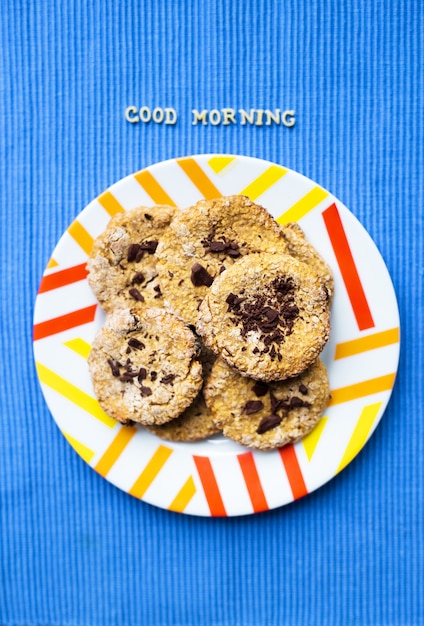 Biscotti di farina d'avena con cioccolato sul buongiorno blu dell'iscrizione del tovagliolo