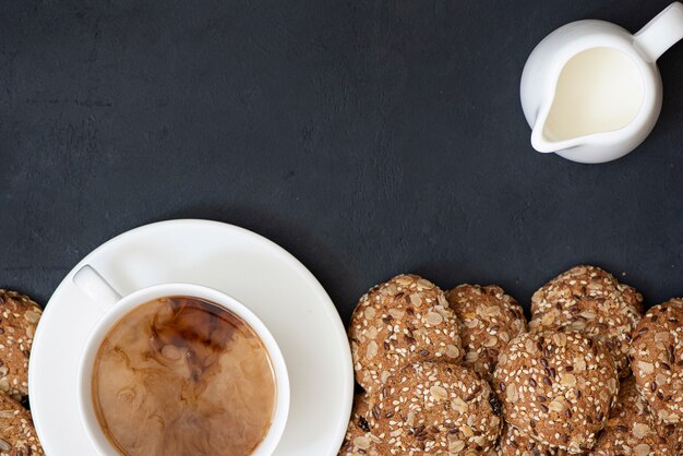 Biscotti di farina d'avena con semi e una tazza di caffè con latte, vista dall'alto