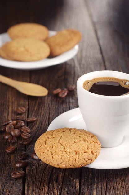 Biscotti di farina d'avena e tazza di caffè caldo sul tavolo di legno scuro