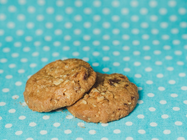 Biscotti di farina d&#39;avena e uva passa su sfondo blu pastello a pois.