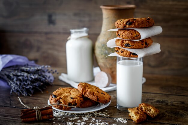 Biscotti di farina d'avena fatti in casa con noci e uvetta e bicchiere di latte su fondo di legno scuro