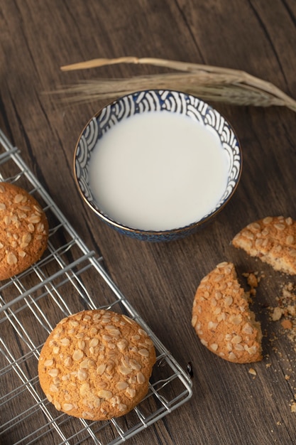 Biscotti di farina d'avena fatti in casa con semi e ciotola di latte fresco sulla tavola di legno