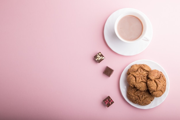 Biscotti di farina d'avena fatti in casa con una tazza di cacao su uno sfondo pastello rosa. vista dall'alto, copia spazio.