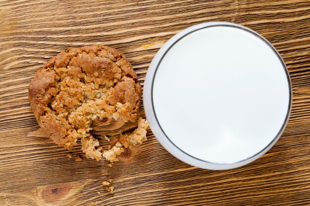 Biscotti di grano croccanti sbriciolati su un tavolo di legno, cibo da vicino, un bicchiere di latte bianco per dare un gusto migliore alla pasticceria