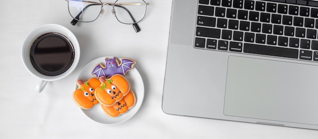 Biscotti di Halloween caffè caldo e computer portatile su sfondo bianco Buon Halloween shopping online Ciao ottobre autunno autunno Festa festiva e concetto di vacanza