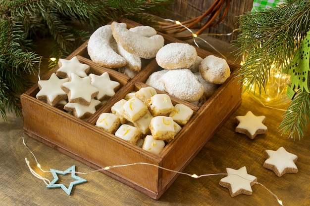 Biscotti di Natale assortiti: stelle di cannella, mezzaluna alla vaniglia, cubetti di stollen e zenzero in una scatola di legno. Stile rustico.