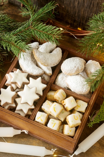 Biscotti di Natale assortiti: stelle di cannella, mezzaluna alla vaniglia, cubetti di stollen e zenzero in una scatola di legno. Stile rustico.