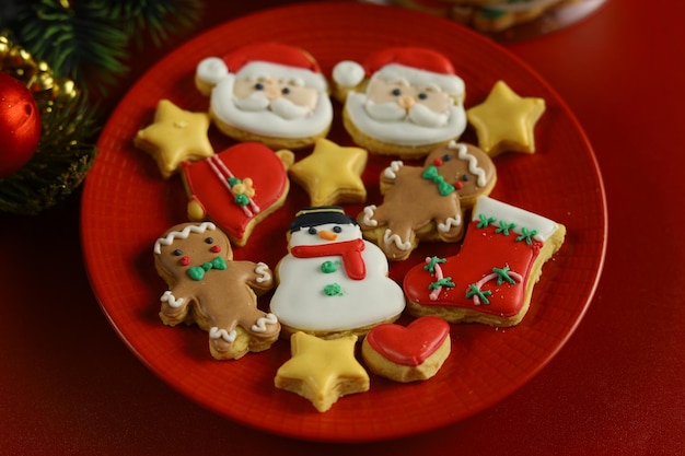 Biscotti di Natale con decorazione di glassa reale con sfondo rosso