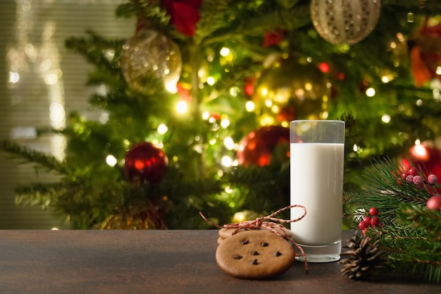 Biscotti di Natale e latte per Babbo Natale vicino all'albero di Natale