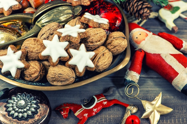Biscotti di Natale e noci con decorazioni vintage su fondo in legno. immagine dai toni in stile retrò