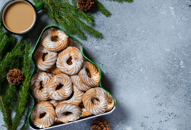 Biscotti di Natale in una scatola sotto forma di un albero di Natale. Rami verdi con pigne.