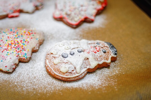 Biscotti di Natale spruzzati di zucchero di ghiaccio su un foglio da forno albero di Natale e biscotto dell'uomo di neve