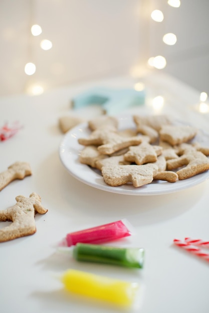 Biscotti di Natale su un piatto bianco con glassa colorata Sfondo di biscotti di Natale Smalto di biscotti al forno in tubi di zucchero filato e luci