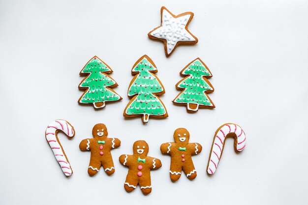 Biscotti di pan di zenzero fatti a mano a forma di stelle fiocchi di neve persone calzini personale guanti alberi di Natale cuori per le vacanze di Natale e Capodanno su sfondo di carta bianca