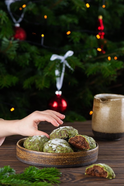 Biscotti di panpepato al cioccolato con matcha in glassa alla menta in un piatto con una mano allungata di un bambino