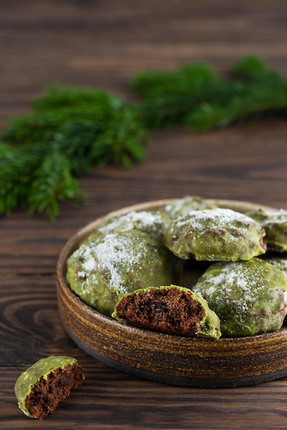 Biscotti di panpepato alla menta fatti in casa con matcha e cioccolato con rami di abete su un tavolo di legno