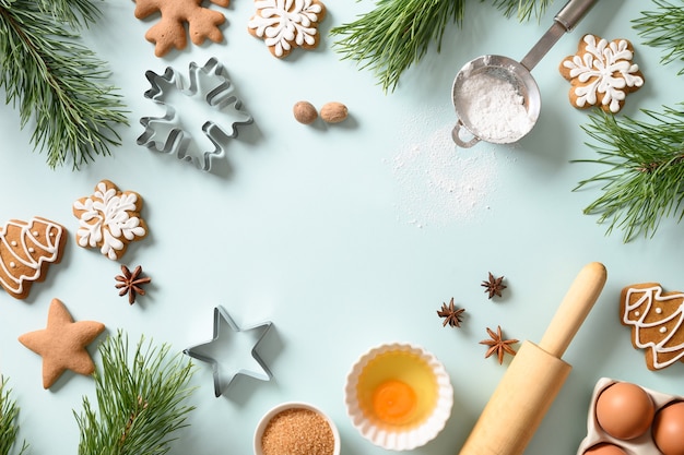 Biscotti di panpepato di Natale con ingredienti per cucinare in fondo azzurro. Buon Natale e Felice Anno nuovo. Copia spazio
