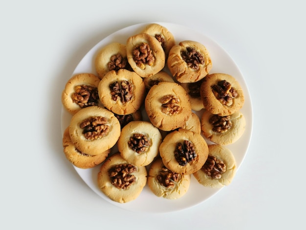 Biscotti di pasta frolla con il primo piano delle noci su un piatto bianco