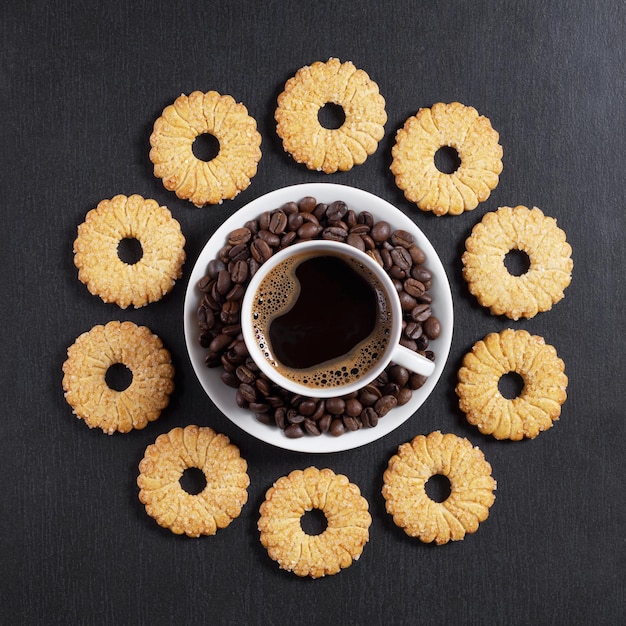 Biscotti di pasta frolla e tazza di caffè sullo sfondo di pietra nera, vista dall'alto