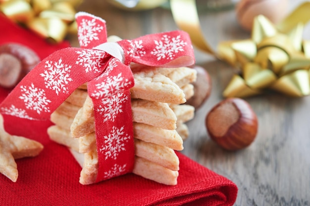 Biscotti di pasta frolla natalizia o stelle di pan di zenzero con nastro rosso decorazione festiva palle di abete e ghirlanda leggera Biscotti tradizionali tedeschi Celebrazione natalizia tradizioni famiglia culinaria