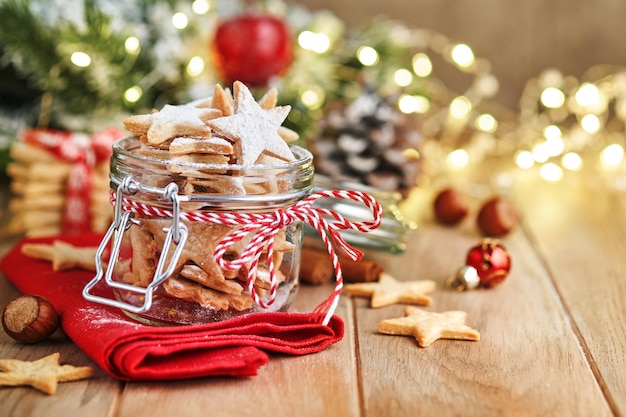 Biscotti di pasta frolla natalizia o stelle di pan di zenzero con nastro rosso decorazione festiva palle di abete e ghirlanda leggera Biscotti tradizionali tedeschi Celebrazione natalizia tradizioni famiglia culinaria