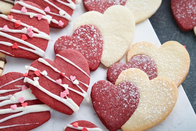 Biscotti di San Valentino Biscotti di pasta frolla all'interno del dolce cuore rosso con glassa al cioccolato su piatto rosa su sfondo grigio Festa della mamma Festa della donna Dolci vacanze cottura Carta di San Valentino Vista dall'alto