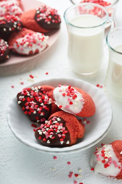 Biscotti di San Valentino Biscotti di pasta frolla con glassa di cioccolato bianco e fondente e spruzzi di cuore su piatto su sfondo bianco Festa della mamma Festa della donna Dolci vacanze cottura Vista dall'alto