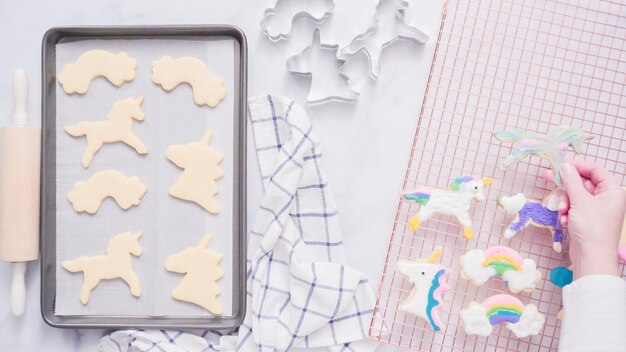 Biscotti di unicorno decorati con glassa reale che si asciuga sullo stendino.