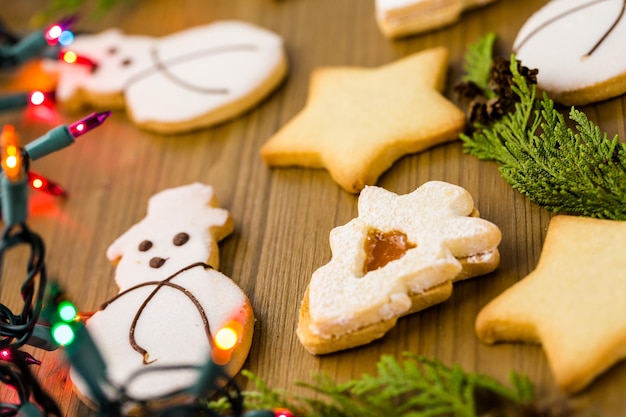 Biscotti di zucchero a forma di pupazzo di neve, stelle e albero di Natale sul tavolo di legno.