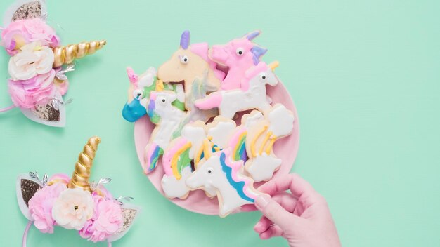 Biscotti di zucchero a forma di unicorno decorati con glassa reale su piatto rosa.