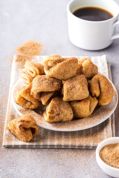 Biscotti di zucchero su un piatto, tazza da caffè, sfondo grigio, formato verticale.