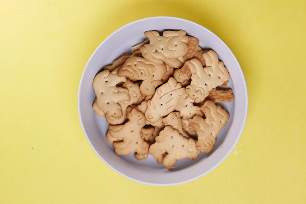 Biscotti dolci di forma animale in una ciotola bianca sfondo giallo