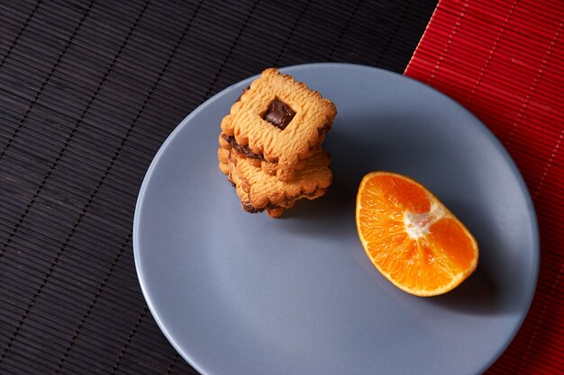 Biscotti e arancia di pepita di cioccolato sul piatto grigio e su stile rosso con la tavola nera