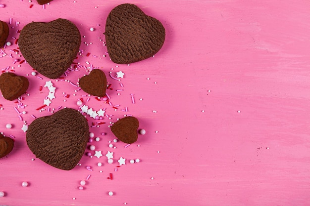 Biscotti e caramelle a forma di cuore su uno sfondo di legno rosa. San Valentino. Posto per il tuo testo.