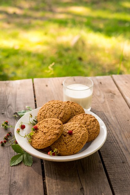 biscotti e latte con fragola sul tavolo di legno con sfondo verde concetto di ricreazione