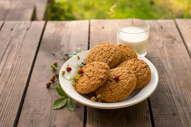 biscotti e latte con fragola sul tavolo di legno con sfondo verde concetto di ricreazione