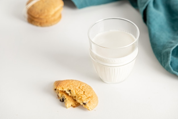 Biscotti e latte in un bicchiere su un tavolo bianco con un tovagliolo