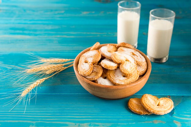 Biscotti e latte vicino alle spighette di grano sul tavolo