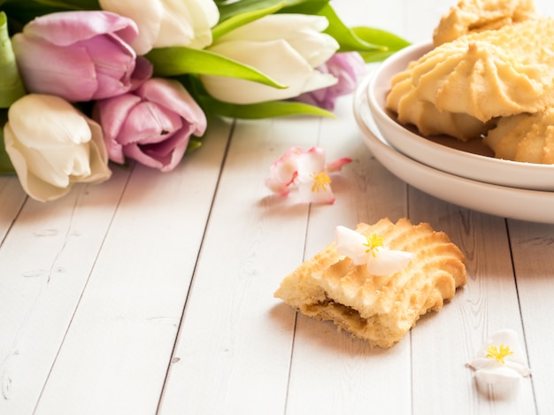 Biscotti e tulipani su un tavolo di legno.