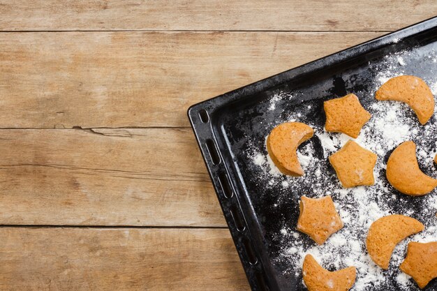 Biscotti fatti a mano su una teglia da forno su una superficie di legno. Vista piana, vista dall'alto.